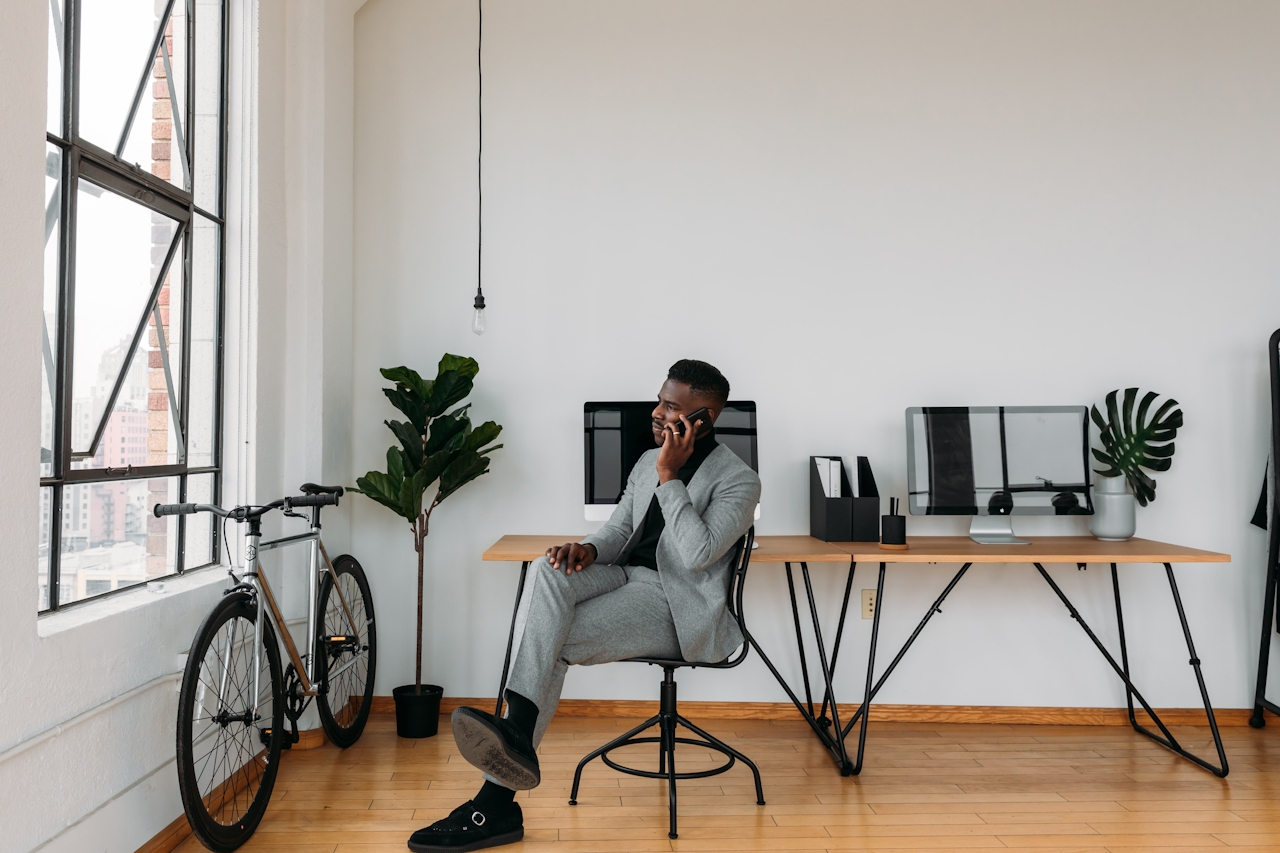 A photo of a man talking on the phone in front of his computer. Used as the featured image for a blog post from Cool Copy Club on how to DIY your brand voice and messaging strategy.